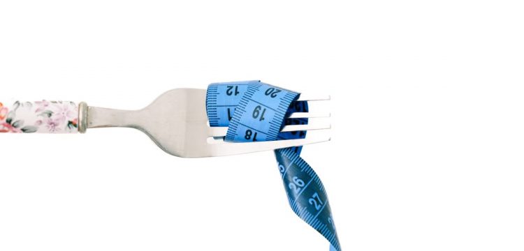 A close-up of a fork wrapped in blue measuring tape, symbolizing diet and weight management.